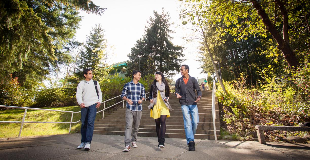 Four students walk across campus together