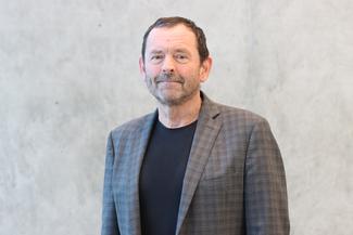 James Cassels smiling, wearing a grey suit in an airy modern room